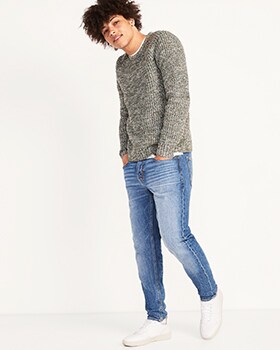 A model wears Relaxed Slim Taper style denim and grey sweater