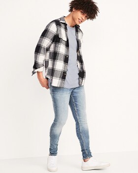 A model wears Super-Skinny style jeans with a button up plaid shirt over a grey t-shirt