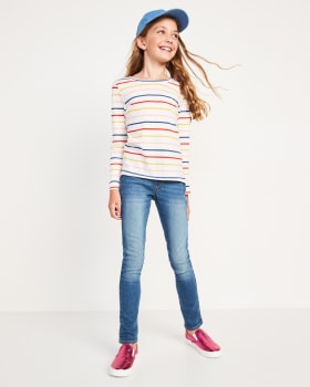 A girl model is wearing a striped fleece, a hat and a skinny jeans.