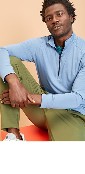 A model wearing a light blue half-zip activewear top and khaki colored activewear pants
