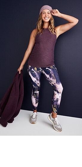 A maternity model wears purple patterned full-panel PowerSoft side-pocket 7/8-length leggings and a purple maternity Breathe ON racerback tank top