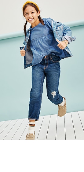 A female model wearing blue tops, ripped jeans and a jean jacket.