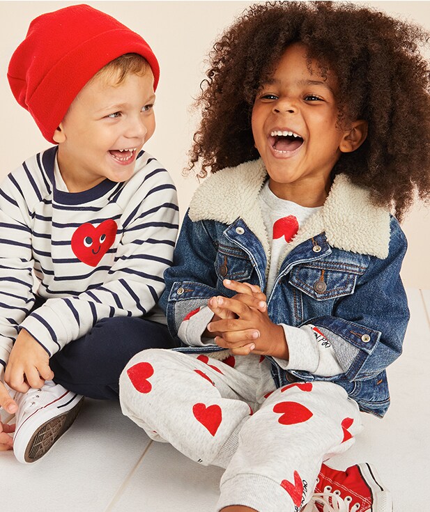 Two young kids dressed in shirts with red hearts.