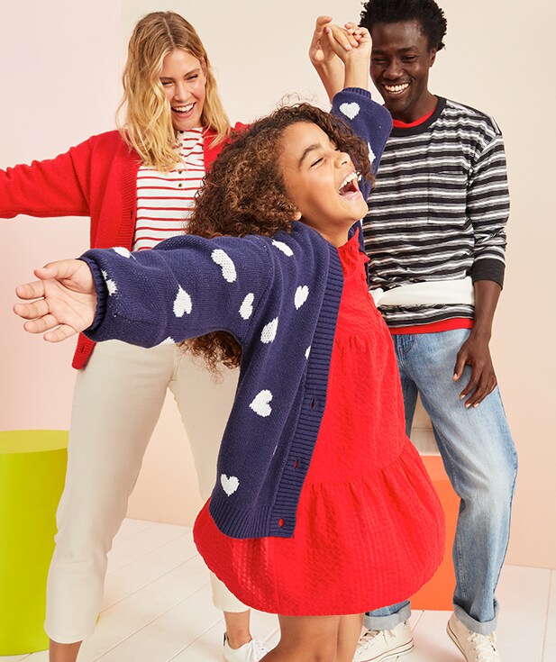 A family dressed in various red, white, and navy blue clothes and dancing around. 