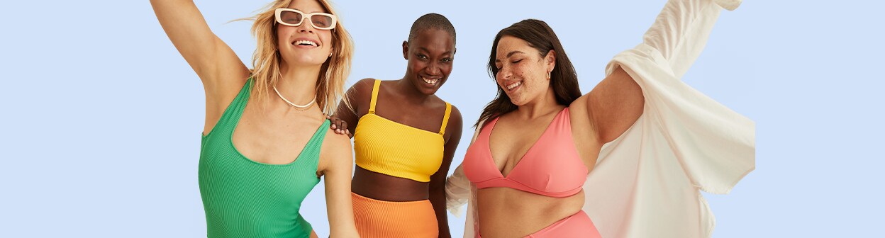 Three models dressed in a variety of different kind of swimsuits.