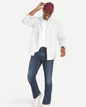 A male model wears Boot-Cut style jeans and a white button-up shirt over a white t-shirt.