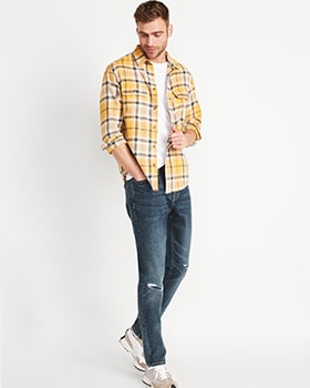 A male model wears Skinny style denim with a yellow, white & black button-up plaid shirt.