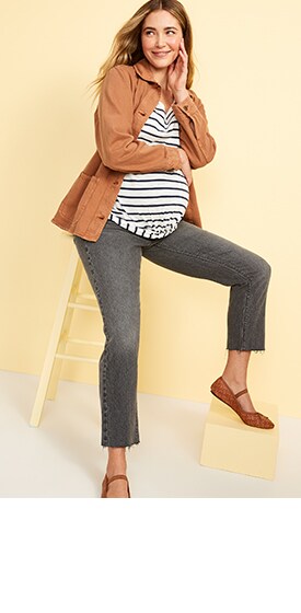 A maternity model wears a white horizontal striped short-sleeved top with grey-washed maternity jeans.