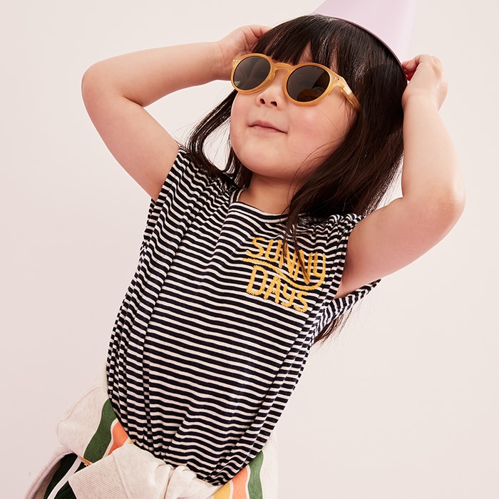 A young girl model wearing stripe top and a sun glasses.