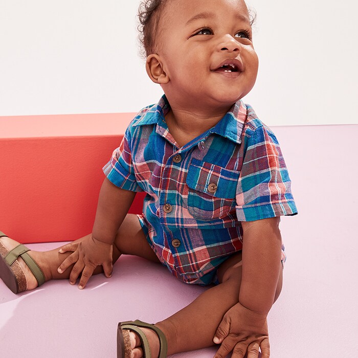 A baby boy model wearing multi color plaid shirt.