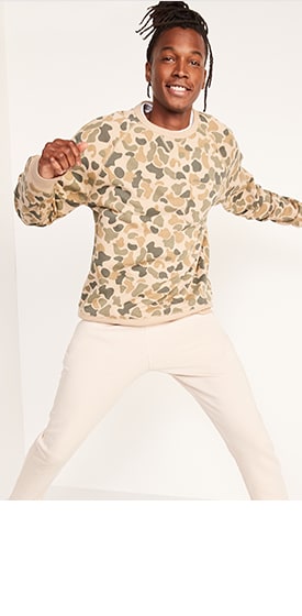 A male model wears a gender-neutral camo French terry sweatshirt and light colored activewear sweatpants
