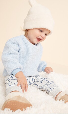 A baby model wearing blue cozy sweatshirt and printed legging set.