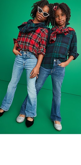 Two young models wearing plaid shirts and flare jeans for girls.