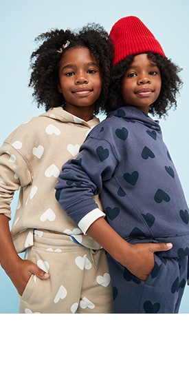 Two young models wearing heart print sweatshirt and sweatpant sets in different colors.
