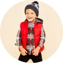 A young male model wearing a red puffer vest & holiday plaid button shirt