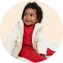 A young female model wearing a red onesie & white sherpa zip up coat