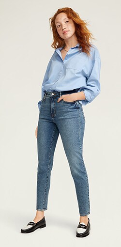 Model in medium-wash, ankle cut slim straight jeans.