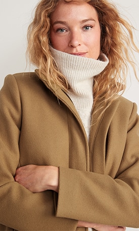 A female model wears a turtleneck and tan coat.