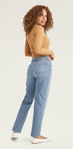 A model in a pair of  medium wash medium rise jeans.