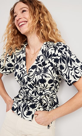 A female model wears a short sleeve black & white floral patterned top.