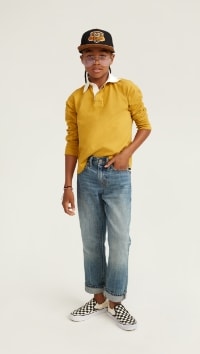 A male model wears Loose style jeans with a yellow rugby style shirt.