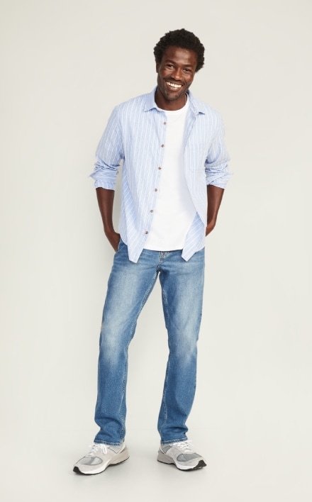A male model wears Straight style jeans and a light colored long sleeve button-up shirt.