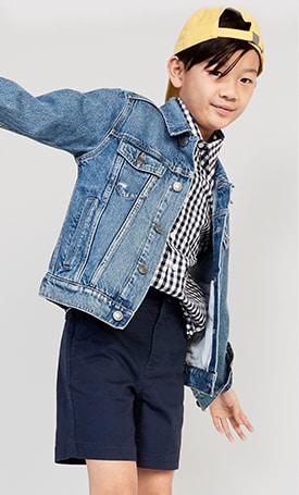 A model wearing button down shirt, straight built-in flex tech Twill short, jean jacket and baseball hat.