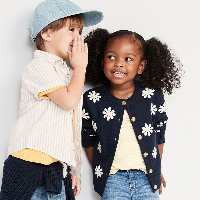 Two young models wearing short-sleeve button-down for toddler boys and flower print cardigan for toddler girls.