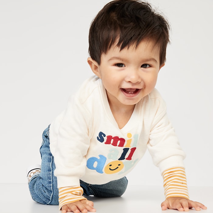 A baby model wearing long-sleeve graphic t-shirt and jeans.