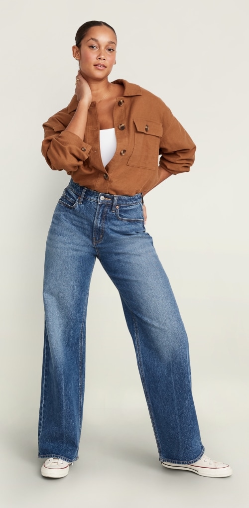 A model dressed in extra high waisted curvy wide leg jean and button down shirt.