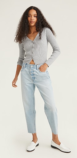 A model in a pair of  light wash raw hem loose fit jeans.
