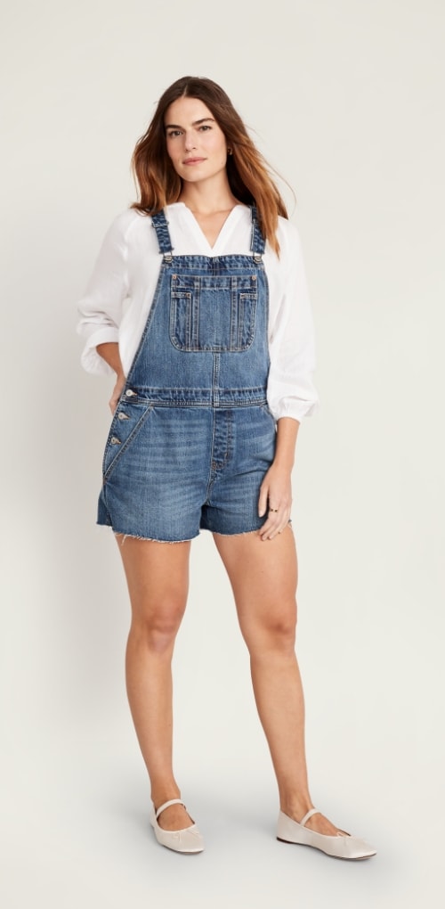 A model dressed in baggy cut off jean shorterall and white shirt.