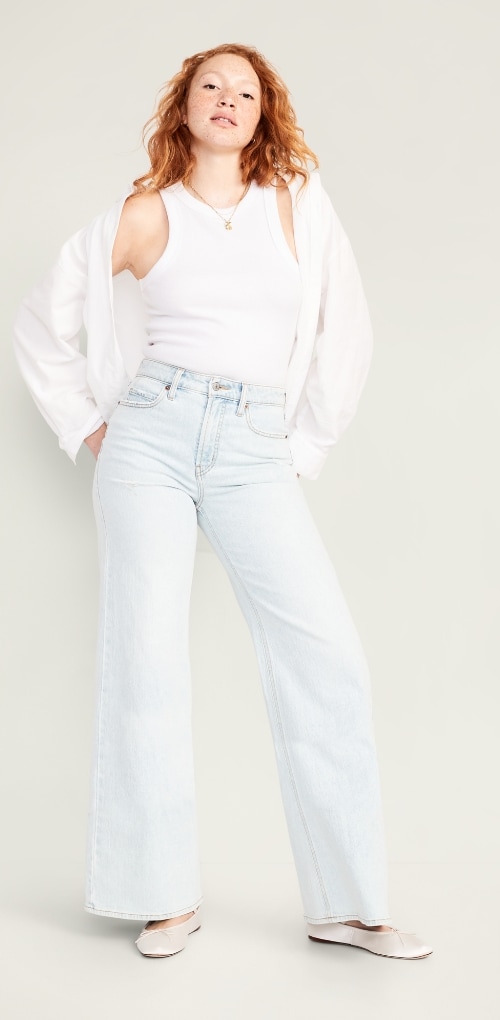 A model wearing extra high waisted A-line wide leg jean, white tank top and shirt.