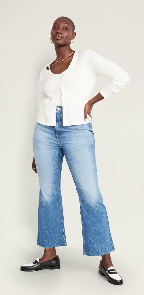 A female model dressed in high rise waisted cropped flare and white sweater.