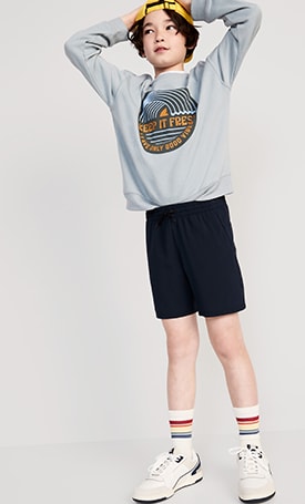A male model dressed in A Graphic Gender-Neutral Crew-Neck Sweatshirt with 'crossroads' graphic & dark activewear shorts.
