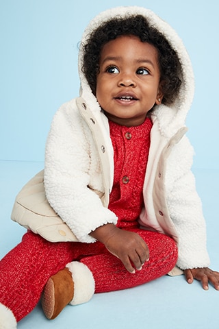 A young model wearing cozy hooded sherpa jacket and red knit sweater and matching bottom.